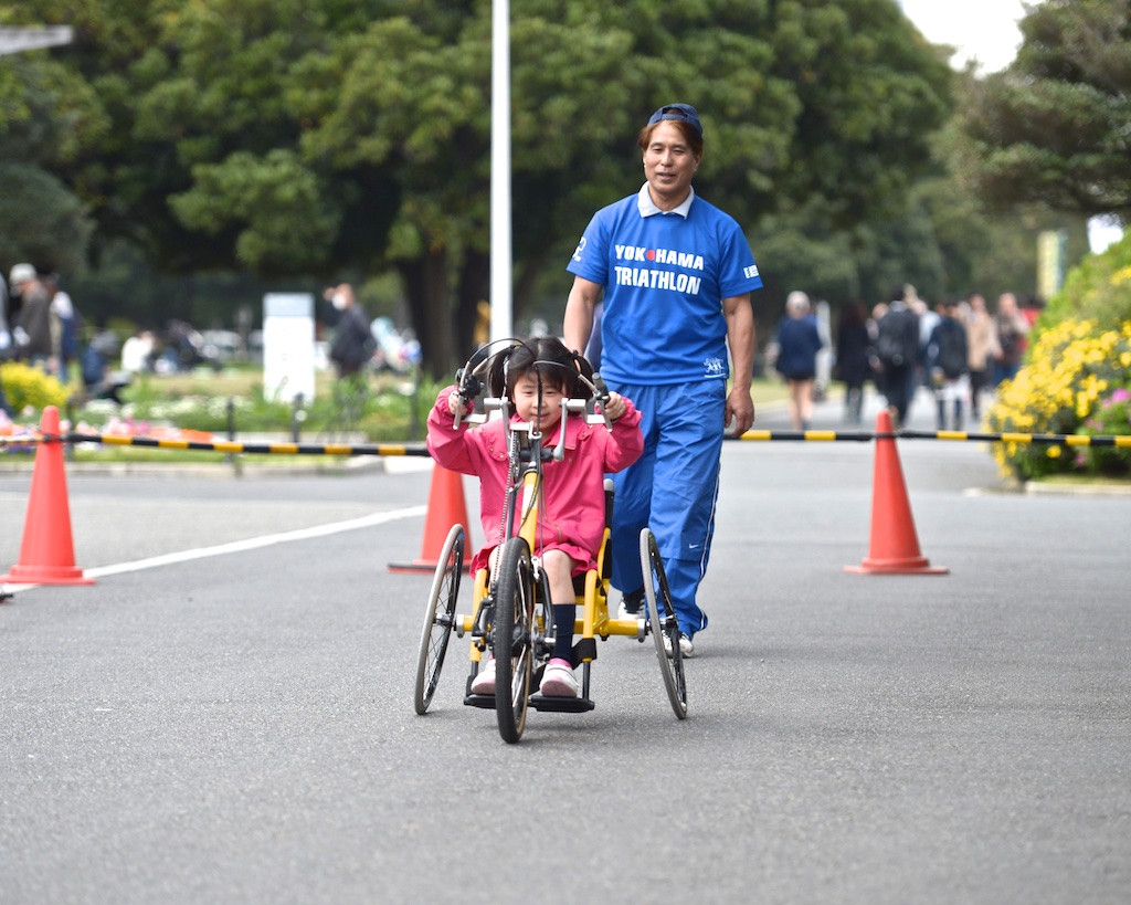 ハンドバイクを体験する子供と横浜市スポーツ文化センターラポールのスポーツ指導員・山川洋氏