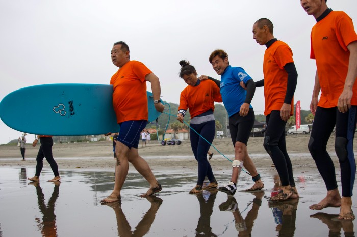 ボランティア・スタッフのサポートで海に向かう選手　（写真・吉田直人）