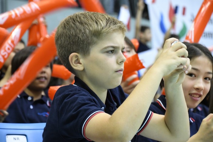 試合をカメラに収めるフランス人学校の小学生。デジカメの画面に集中していた