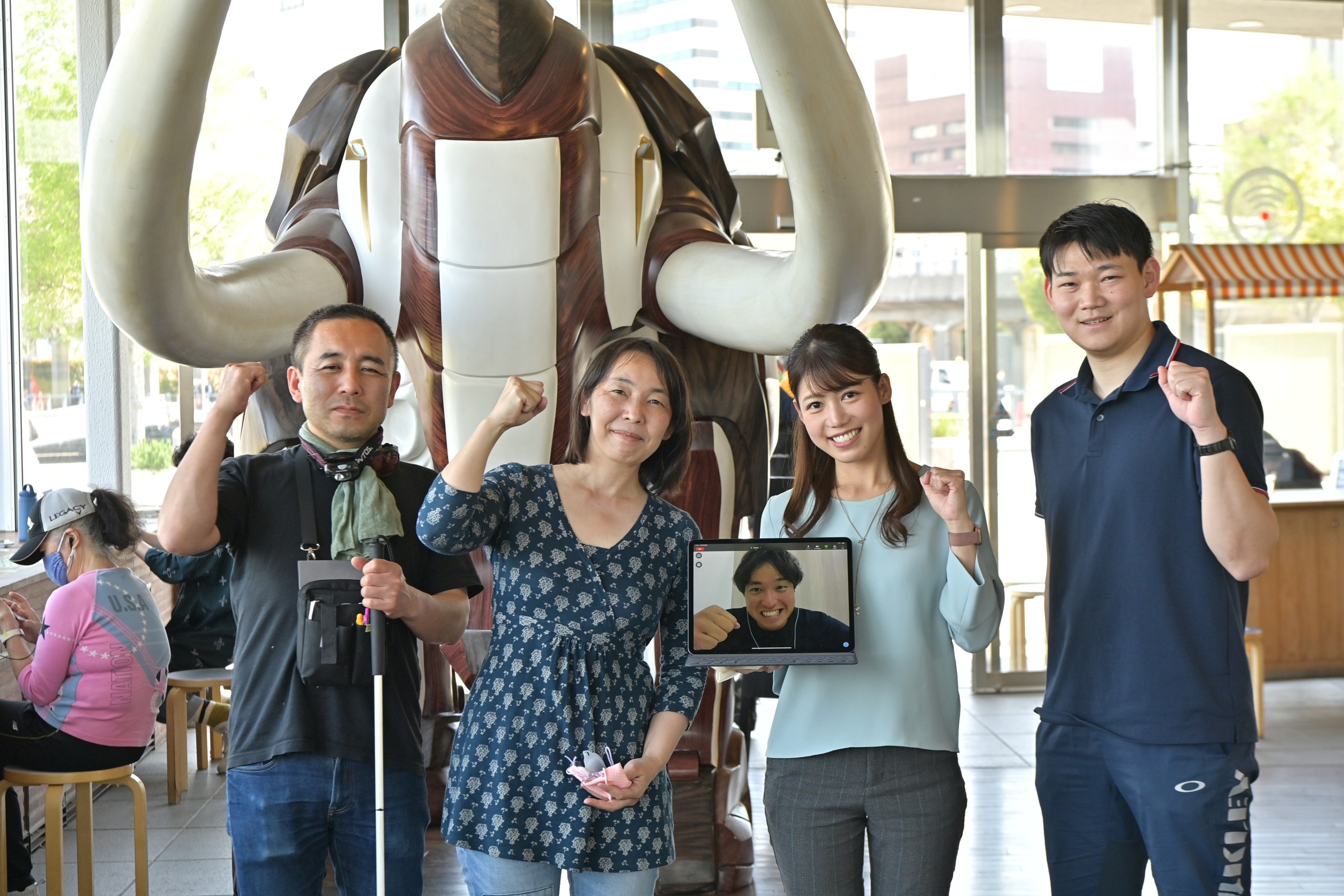 パソコン画面の木村とスタッフ集合写真