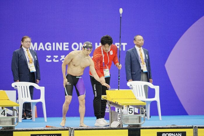 男子100m自由形S11のスタート前、タッパーとともにスタート台に向かう富田宇宙